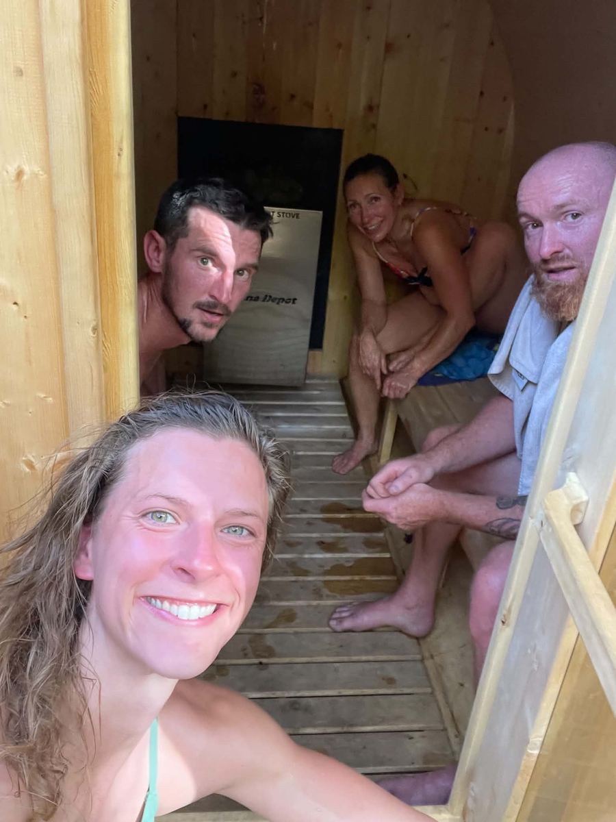Four smiling practitioners inside the wood-fired sauna